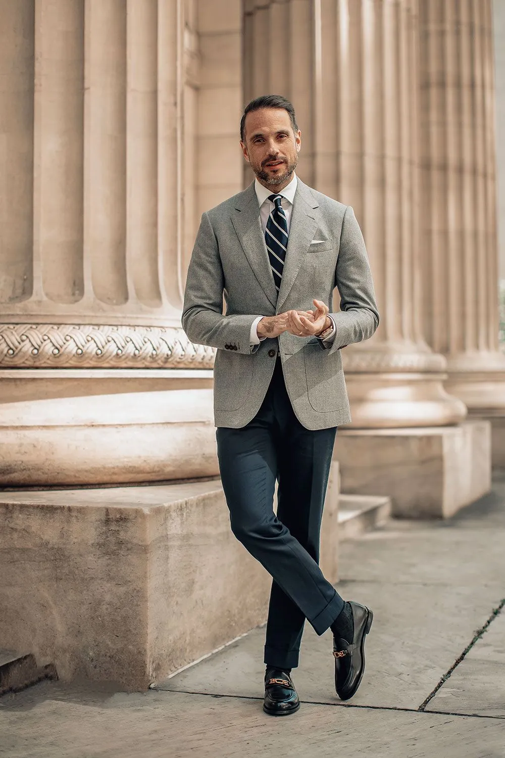 Professional man in tailored gray blazer with dress shirt and striped tie demonstrating timeless business style