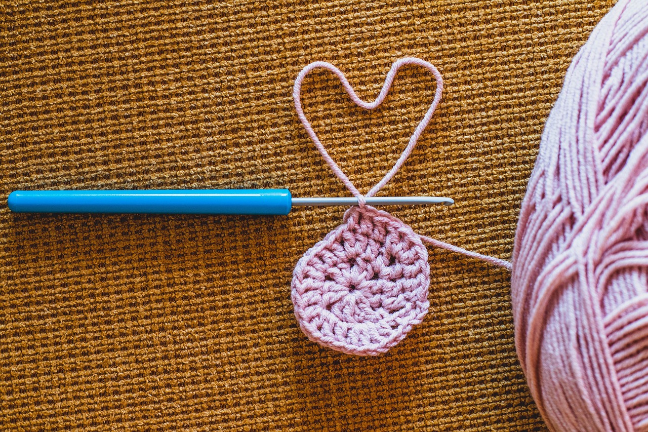 Pink crochet heart with hook and yarn - love for handmade crochet vest patterns