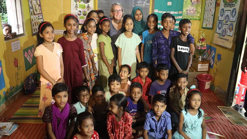 Students seated in a circle inside a rustic BRAC classroom