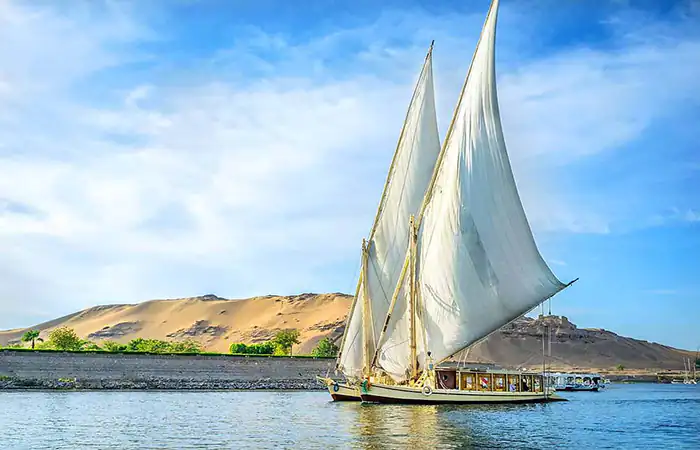 Traditional felucca sailboat on the Nile River in Aswan during a cheap trip in Egypt