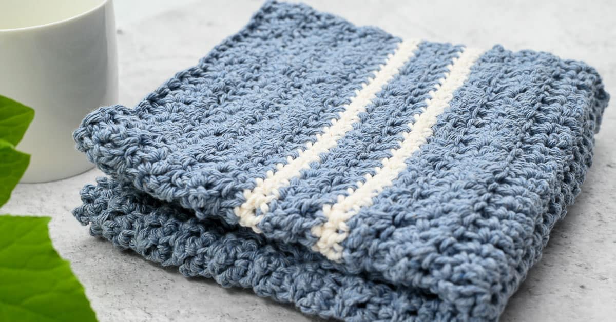 Pastel crochet dishcloths stacked on wooden counter next to bowl of lemons — soft cotton washcloths in pink, blue, yellow and purple