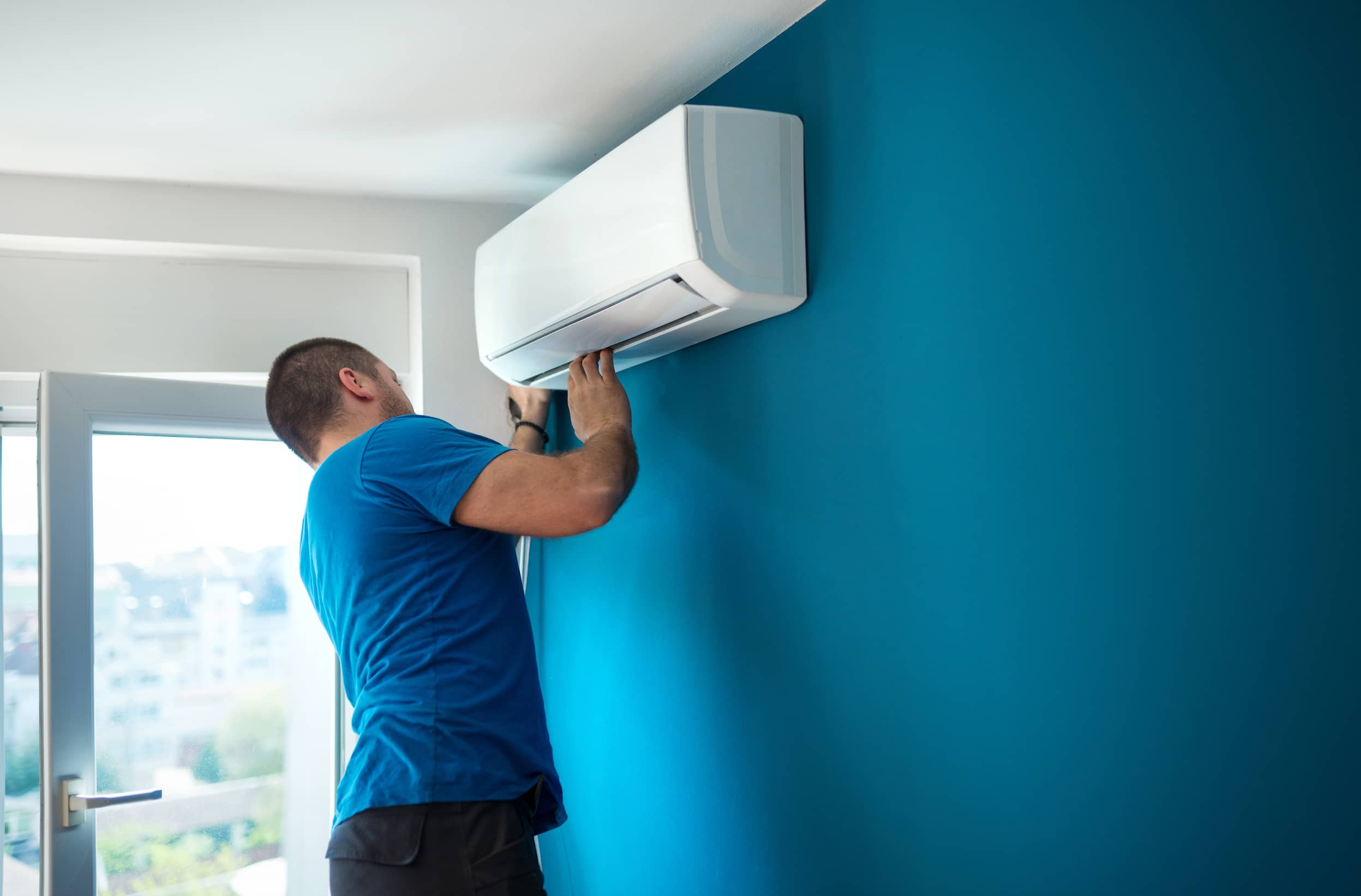 Técnico instalando sistema de climatización en pared de vivienda en AMBA