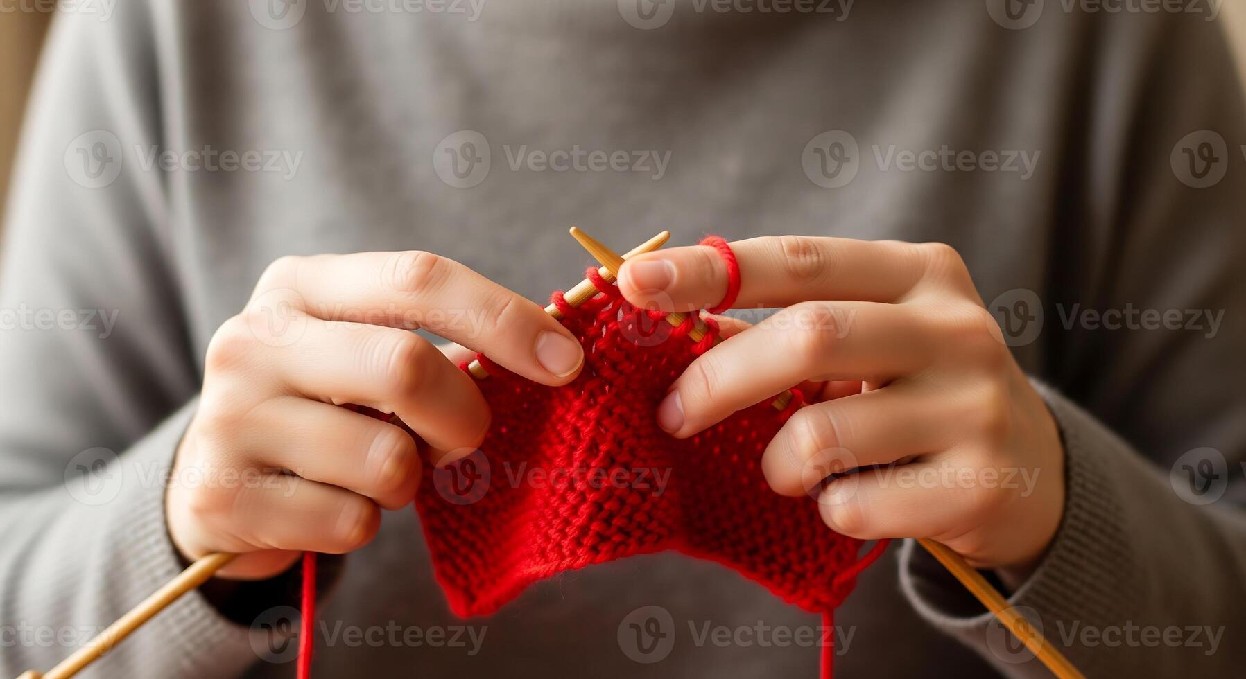 alt="Close-up of hands knitting with bright red wool yarn and wooden needles — knitting therapy and flow state"