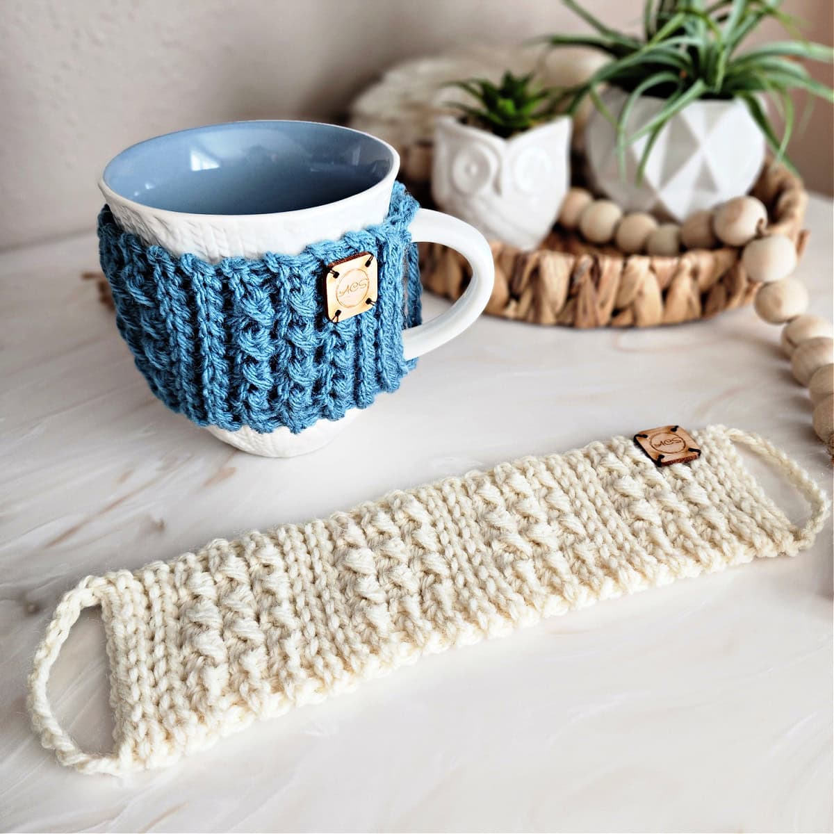 Handmade crochet cup cozy in blue with wooden button on white mug