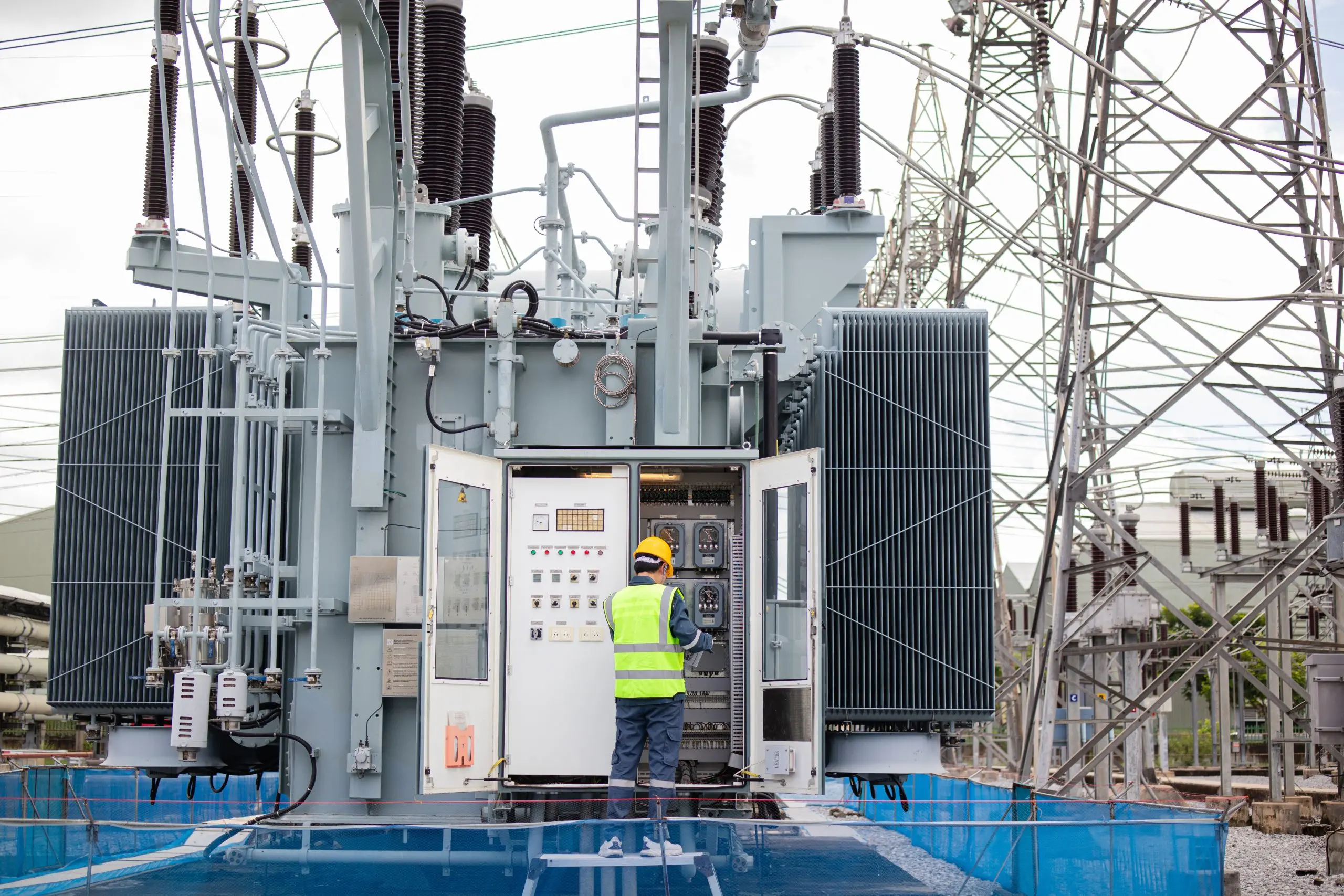 Professional transformer maintenance technician inspecting high-voltage power transformer control panel at industrial substation in Nigeria