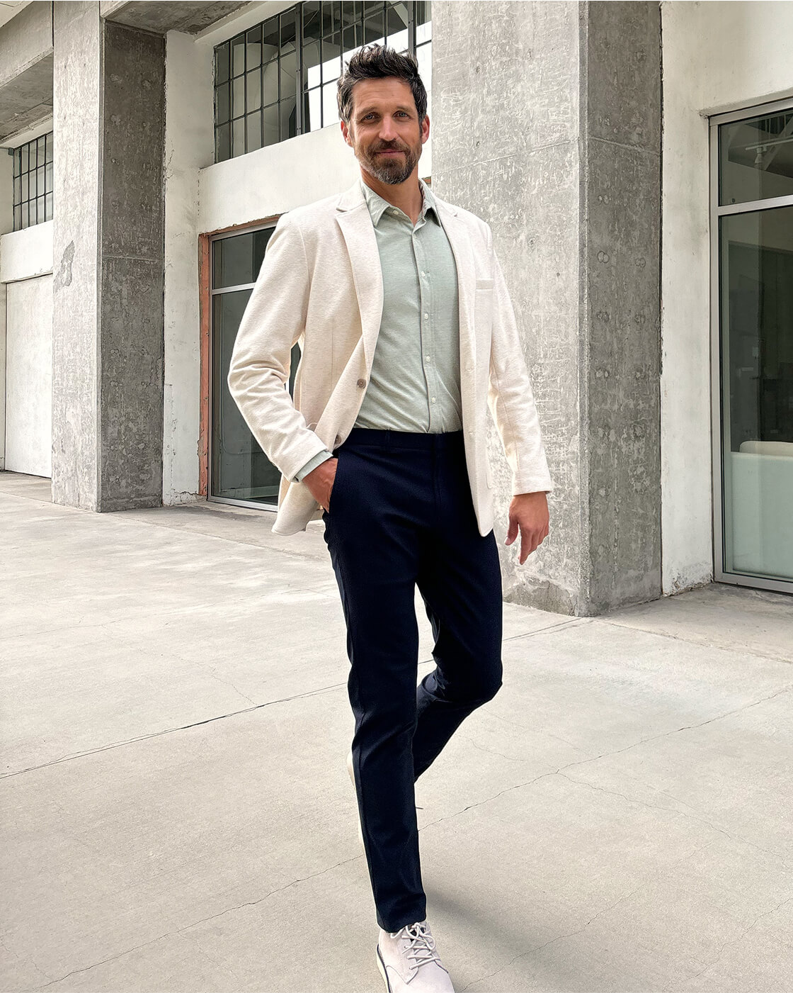 Man in cream blazer with light green dress shirt and navy trousers showing smart casual menswear style
