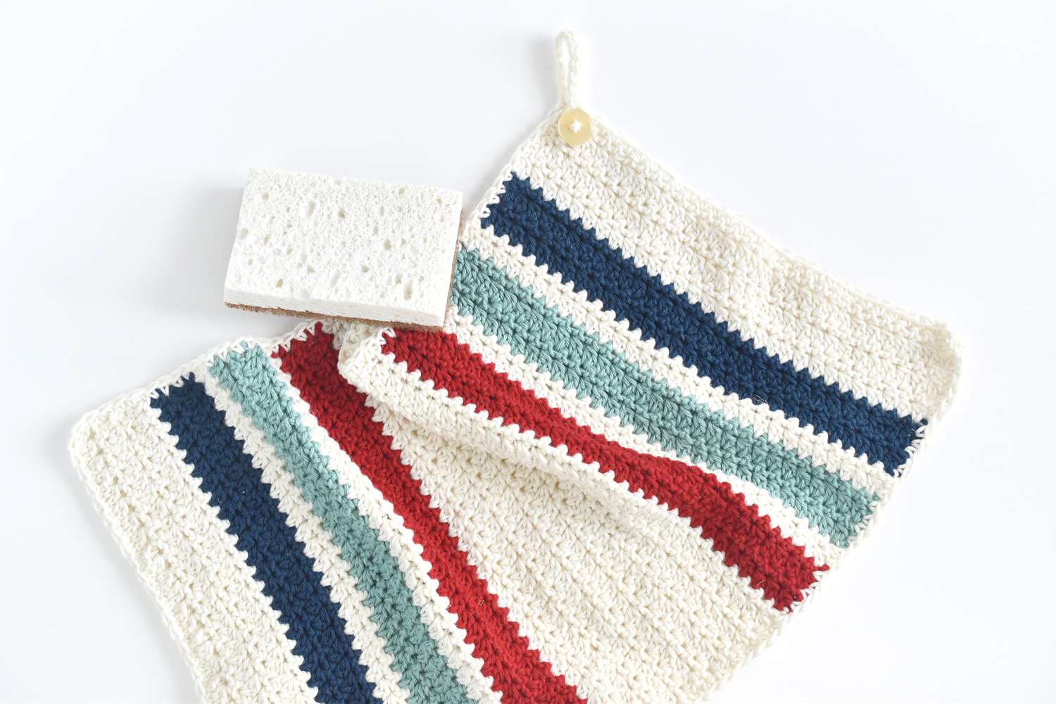 Colorful crochet dishcloths and hand towels in wicker basket on kitchen counter — handmade cotton kitchen linens in green, yellow, blue and striped patterns.